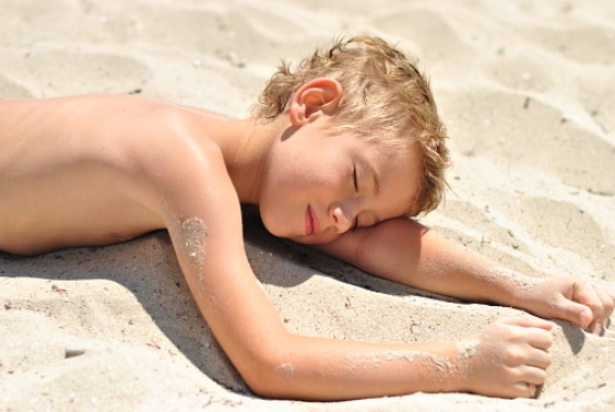 Boy lying on the sand on the bea